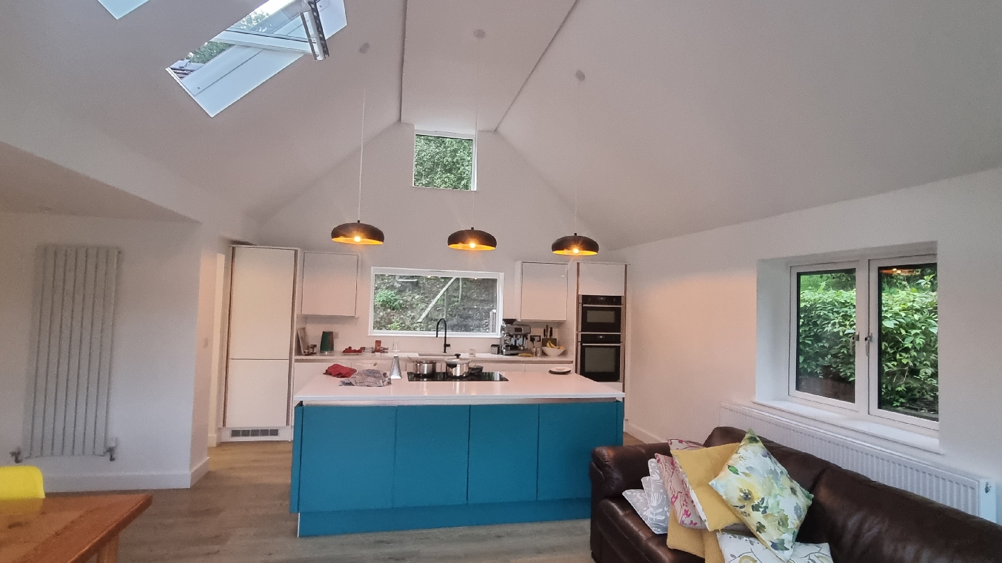 A bright vaulted kitchen with roof windows and a teal island