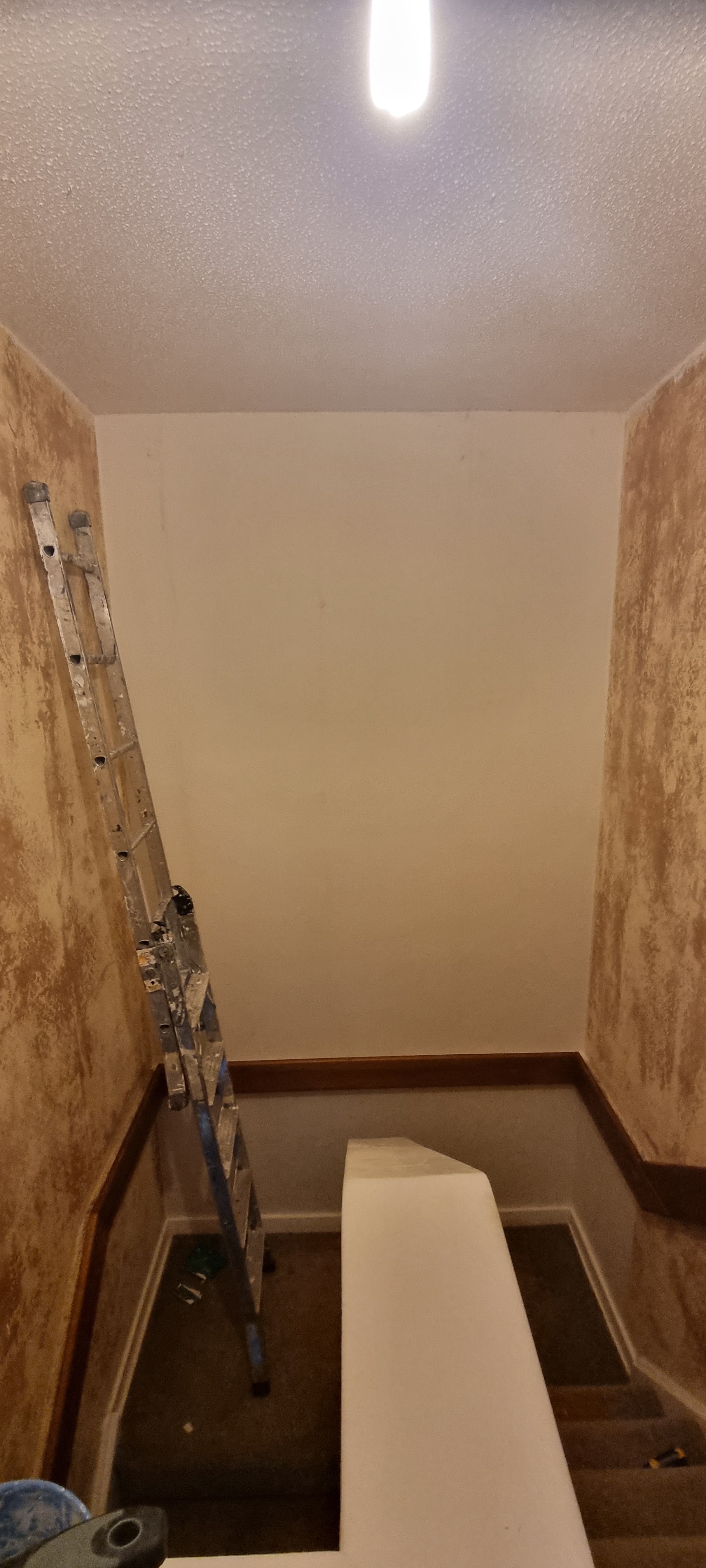A tall stairwell freshly painted, a ladder in place