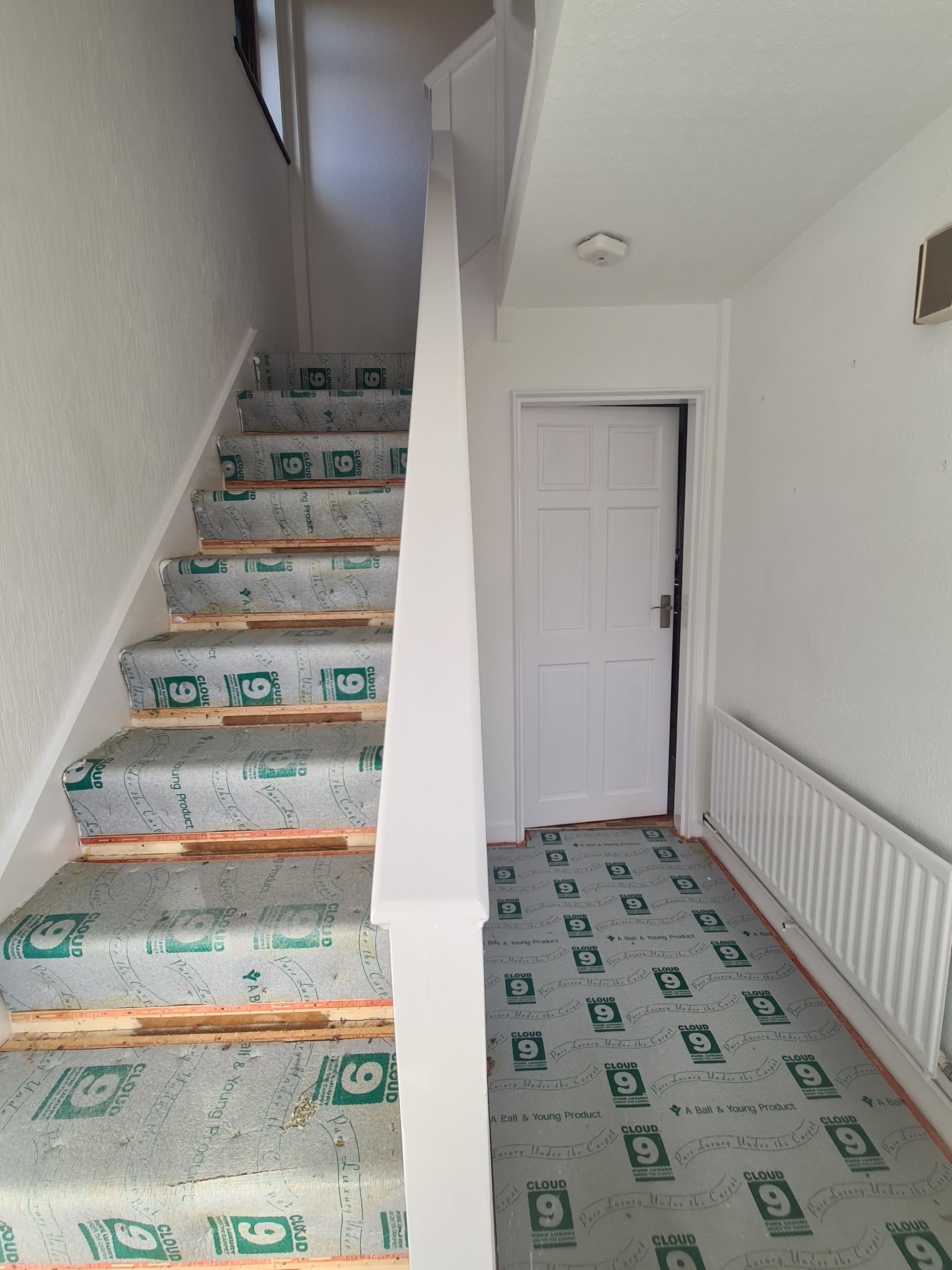 A white staircase and hallway with floor protection on the treads